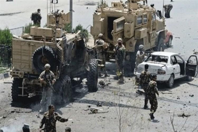 مدرعات تابعة لقوات ناتو وجنود في أفغانستان إلى جانب سيارة مدمرة