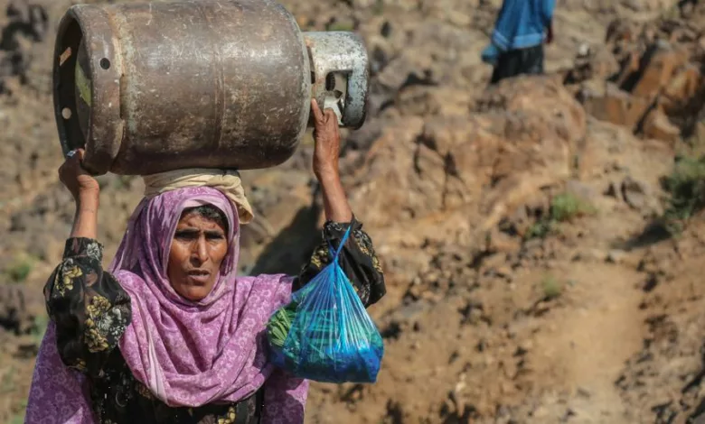 سيدة يمنية تحمل دبة الغاز - غلاف تقرير الإعلام الاقتصادي عن اقتصاد الحرب